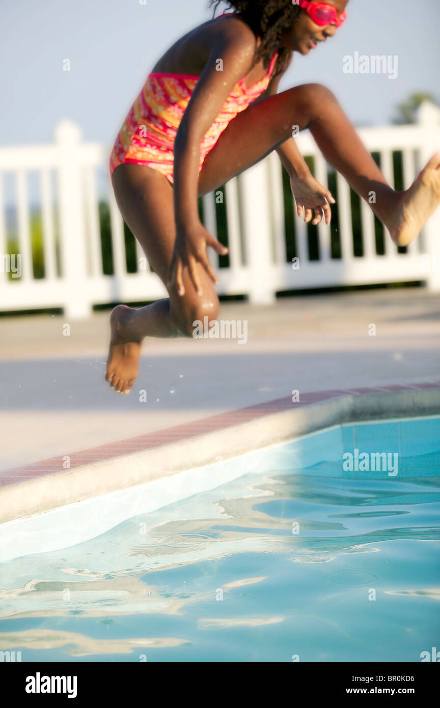 African American girl jumping into a swimming pool. Stock Photo