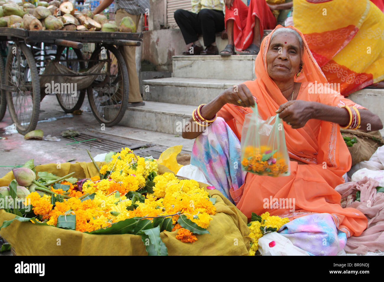 Elderly lady selling Marigold strings (garlands) at the Hindu temple for decorations during Diwali. Stock Photo