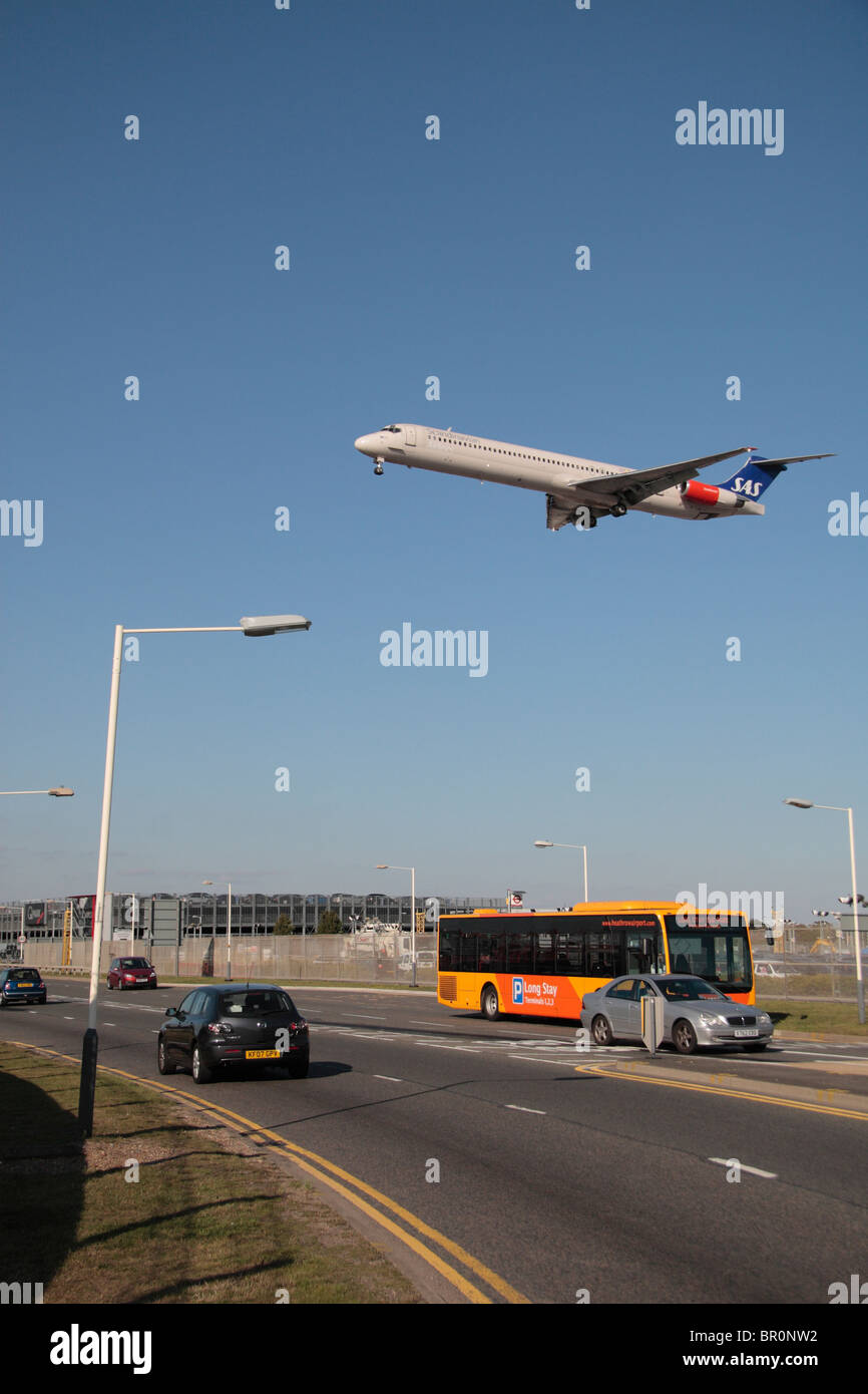 A SAS plane coming in to land at Heathrow Airport, London, passing over buses and cars on the perimeter road. Stock Photo
