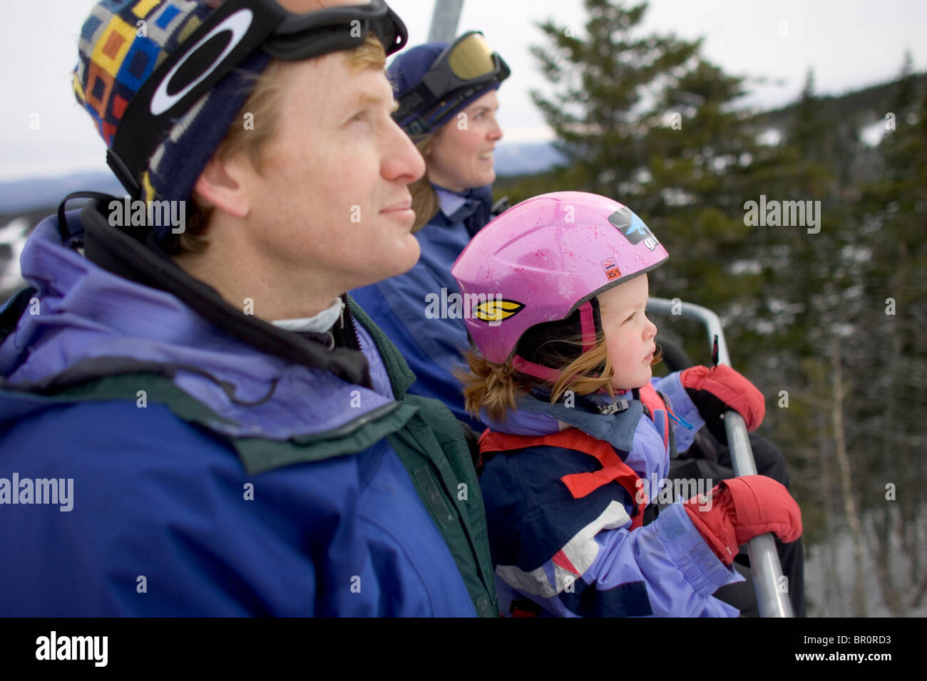 A young girl rides the chairlift with her family at Sunday River in Bethel, Maine. Stock Photo