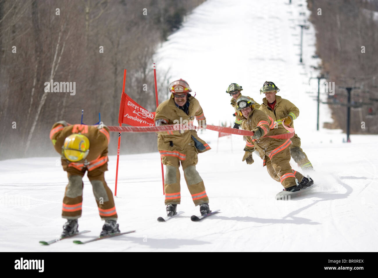 A group of fireman are in the annual fireman hose race at Sunday River ski resort in Bethel, Maine. Stock Photo