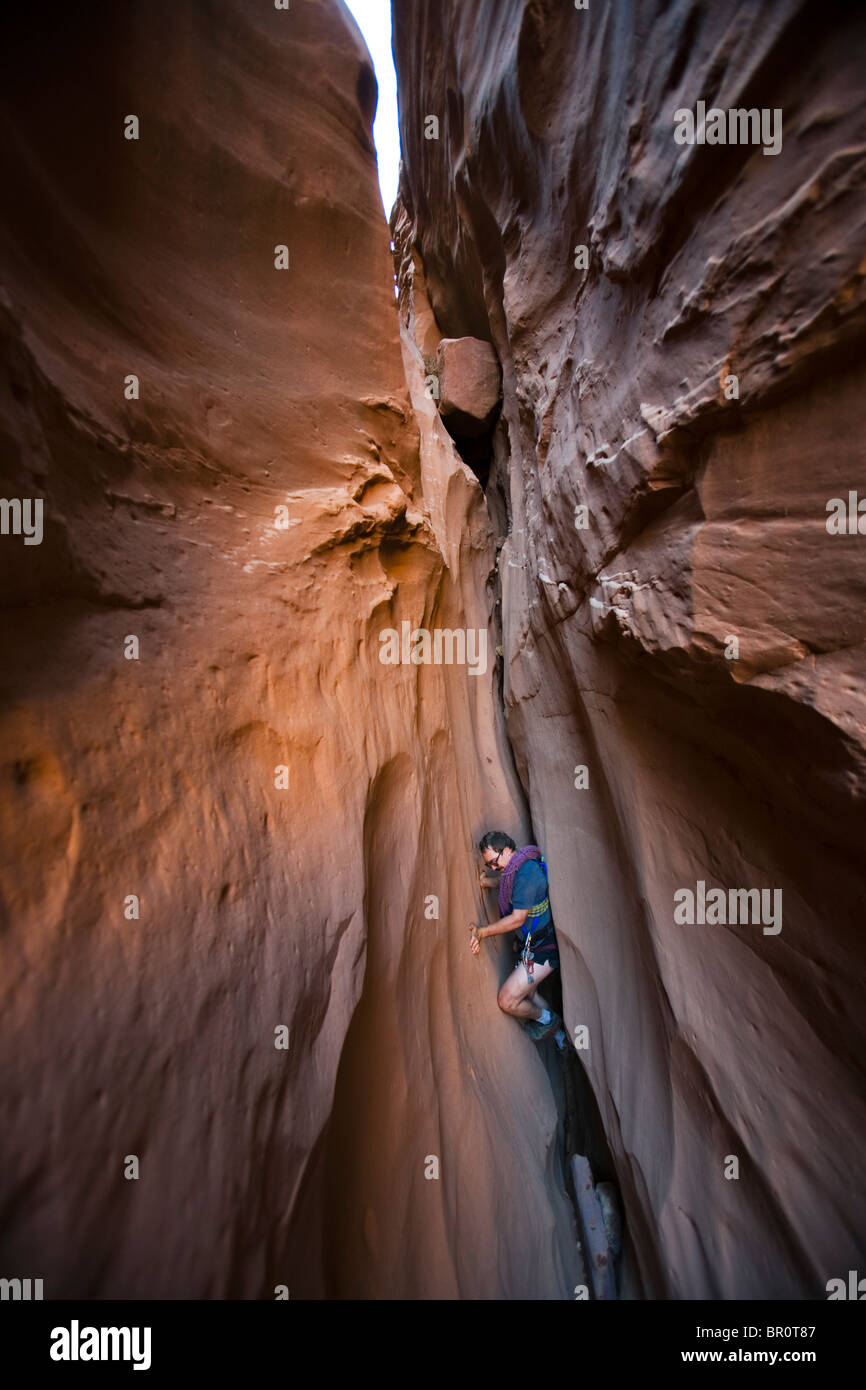 A man chimneying down a slot canyon, Utah. Stock Photo