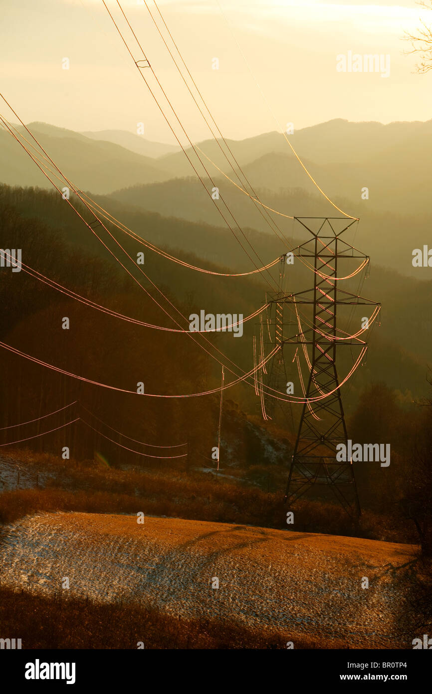 Power transmission lines reflect the sunset glow as they head up and over the Appalachian Trail at Tellico gap near Bryson City, Stock Photo