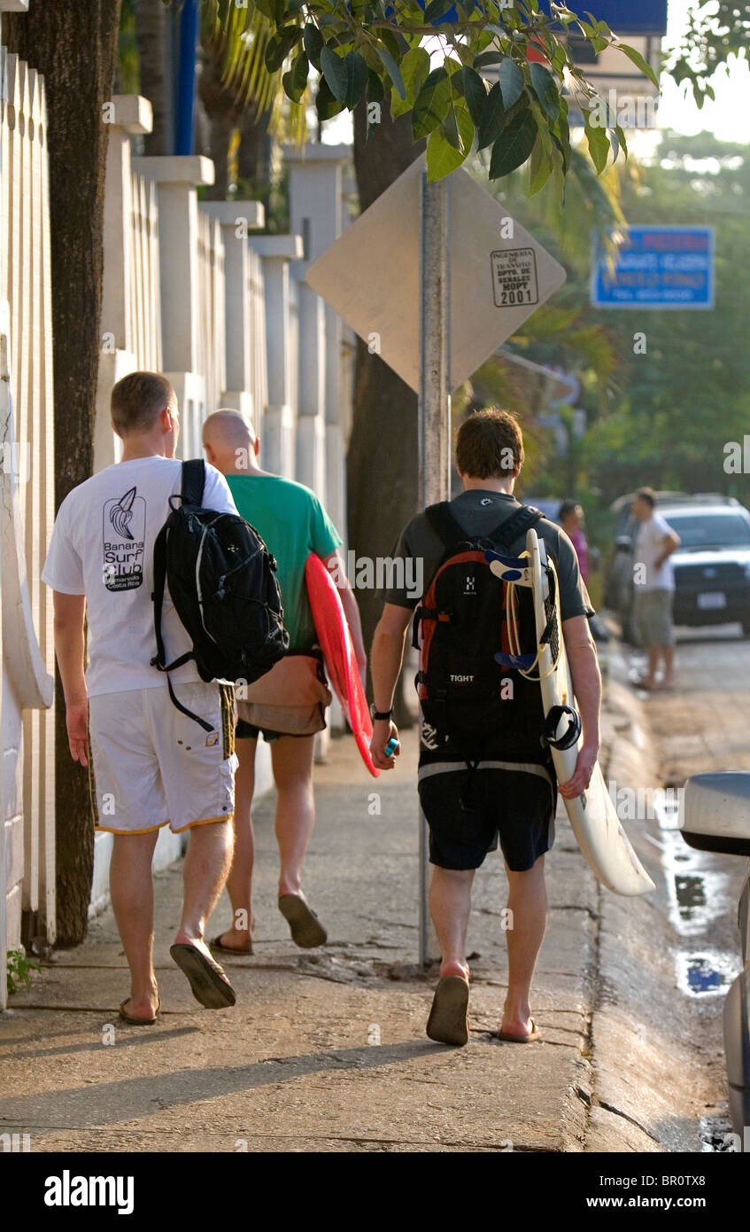 Tourists carry surf boards in the town of Tamarindo on the Northern Pacific Coast of Costa Rica. Stock Photo