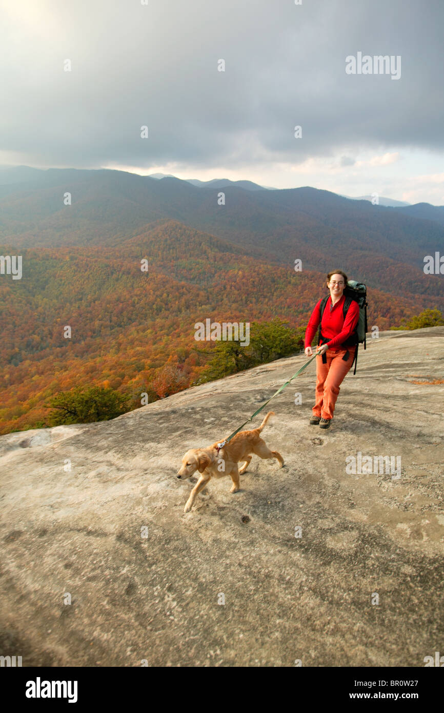 Female hiker with dog amidst the fall colors on top of Looking Glass Rock in the Pisgah National Forest near Brevard, NC. Stock Photo