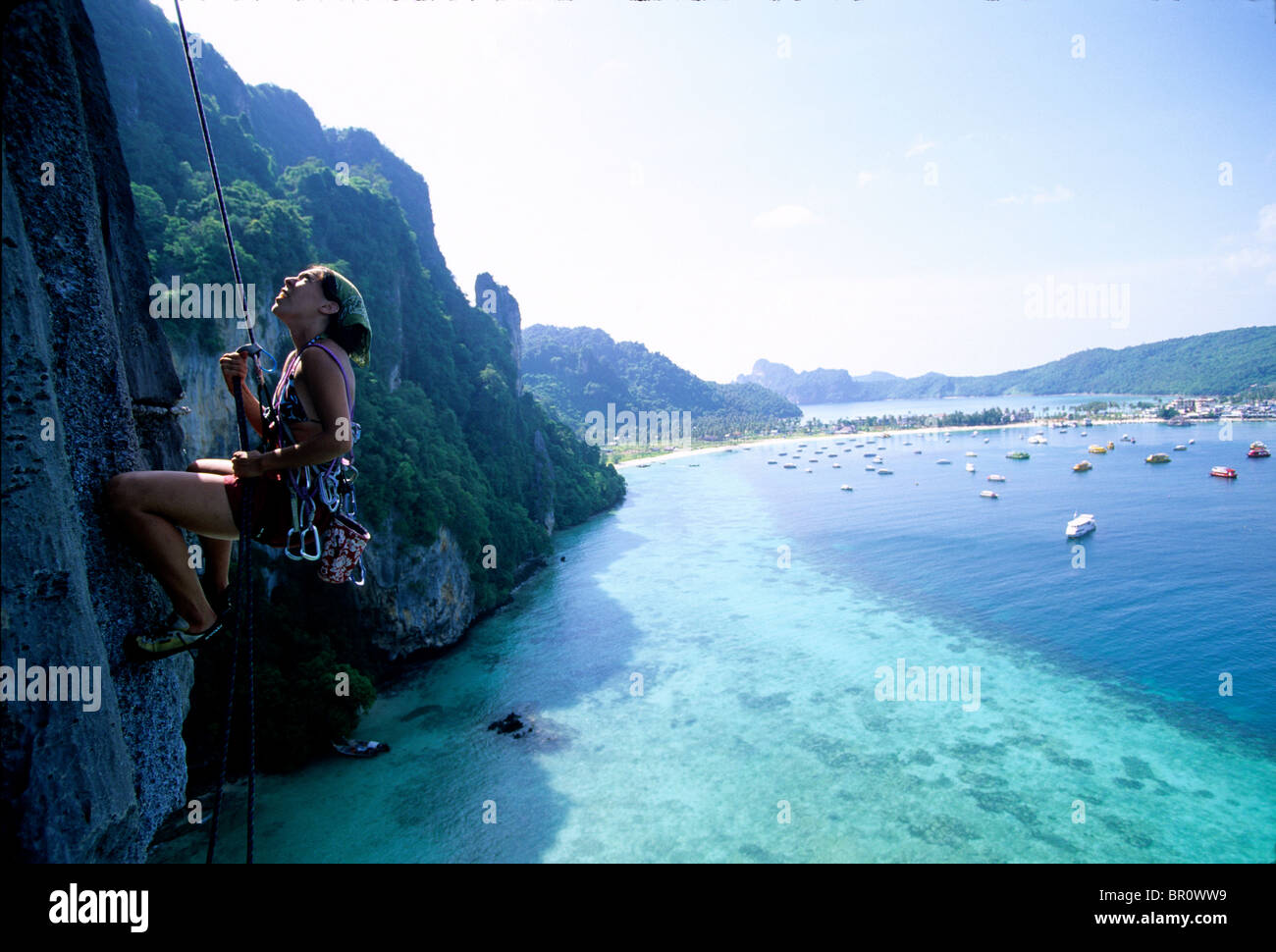 A woman rappels a limestone cliff above the ocean in Thailand Stock ...