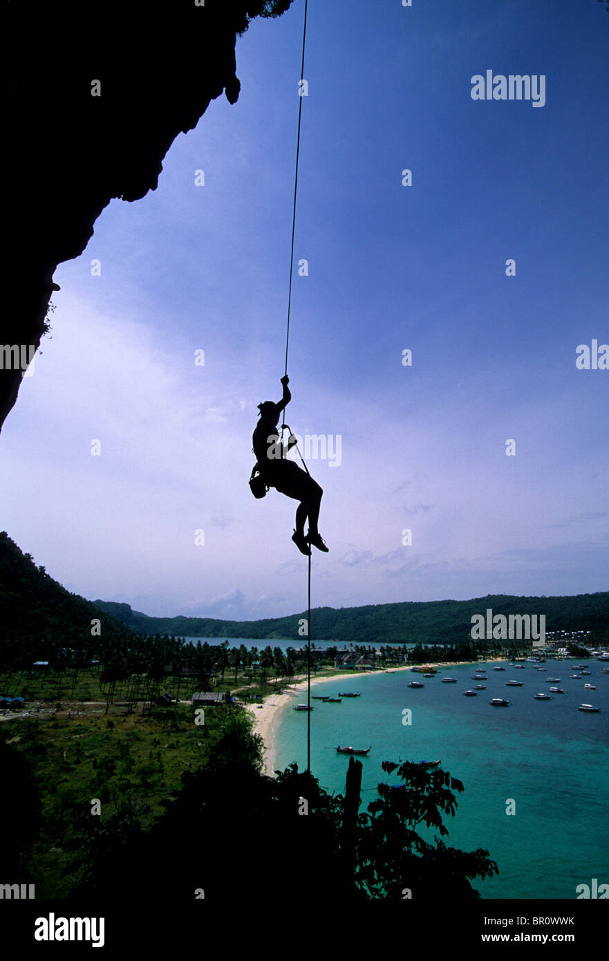 A woman rappels a limestone cliff above the ocean in Thailand Stock ...