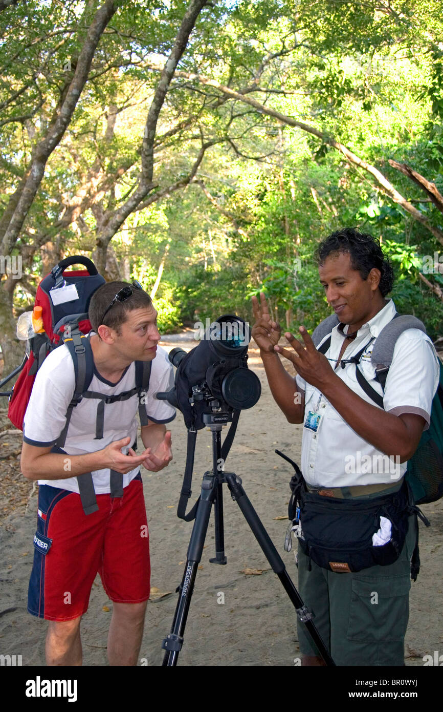 Tourist and nature guide look at wildlife through a telescope in the Manuel Antonio National Park in Puntarenas province, Costa. Stock Photo
