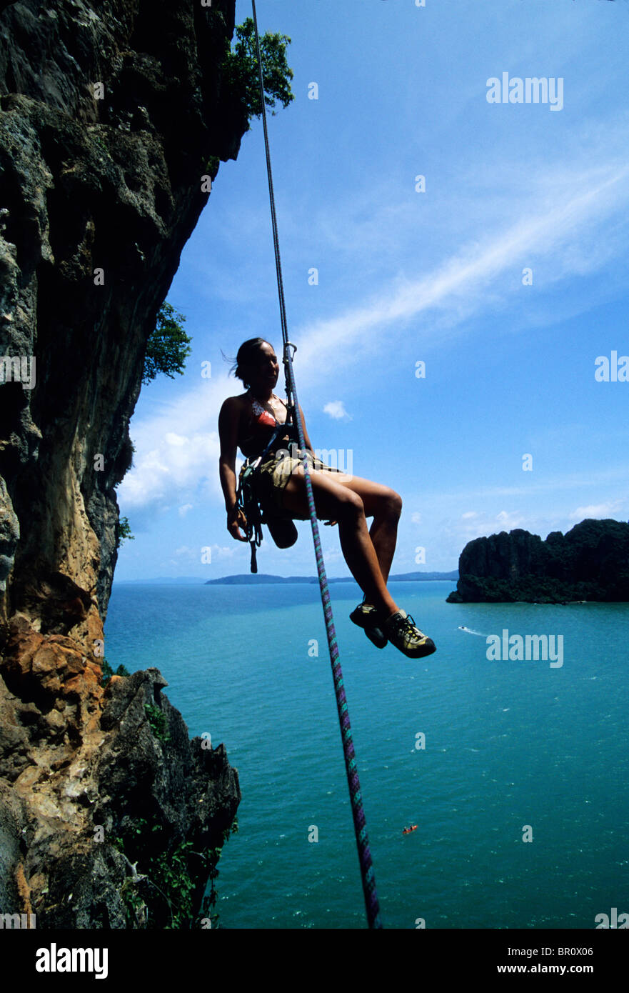 A woman rappels a limestone cliff above the ocean in Thailand Stock ...