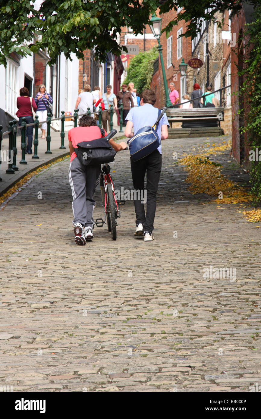 Students pushing a cycle up Steep Hill, Lincoln. Stock Photo