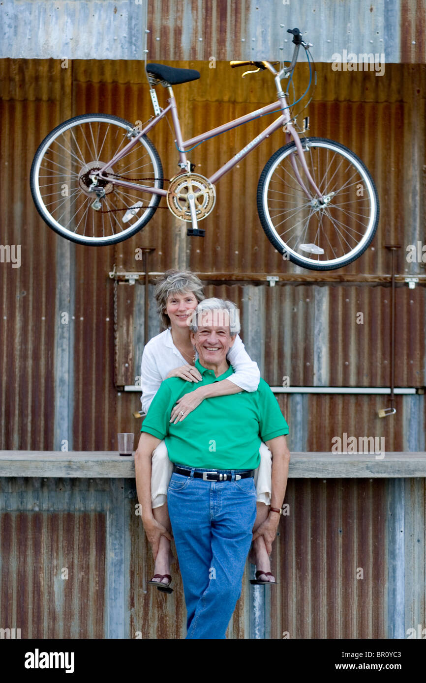 Blue star bike shop san antonio hi-res stock photography and images - An OlDer Couple Hugging Infront Of A BuilDing With A Bike Hung Up BR0YC3