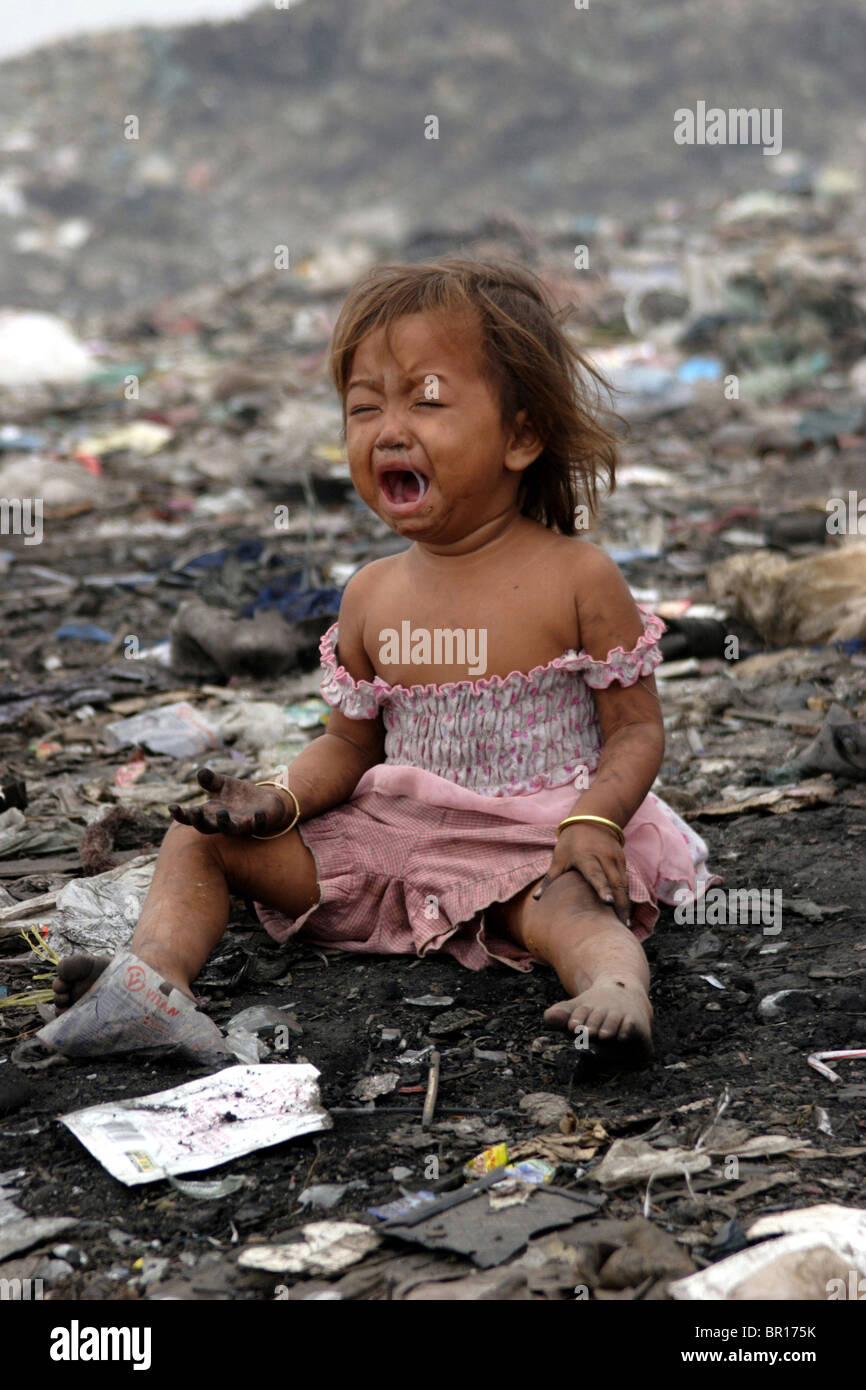 A young girl cries out in pain after receiving an injury to her hand at the Stung Meanchey landfill in Phnom Penh, Cambodia. Stock Photo