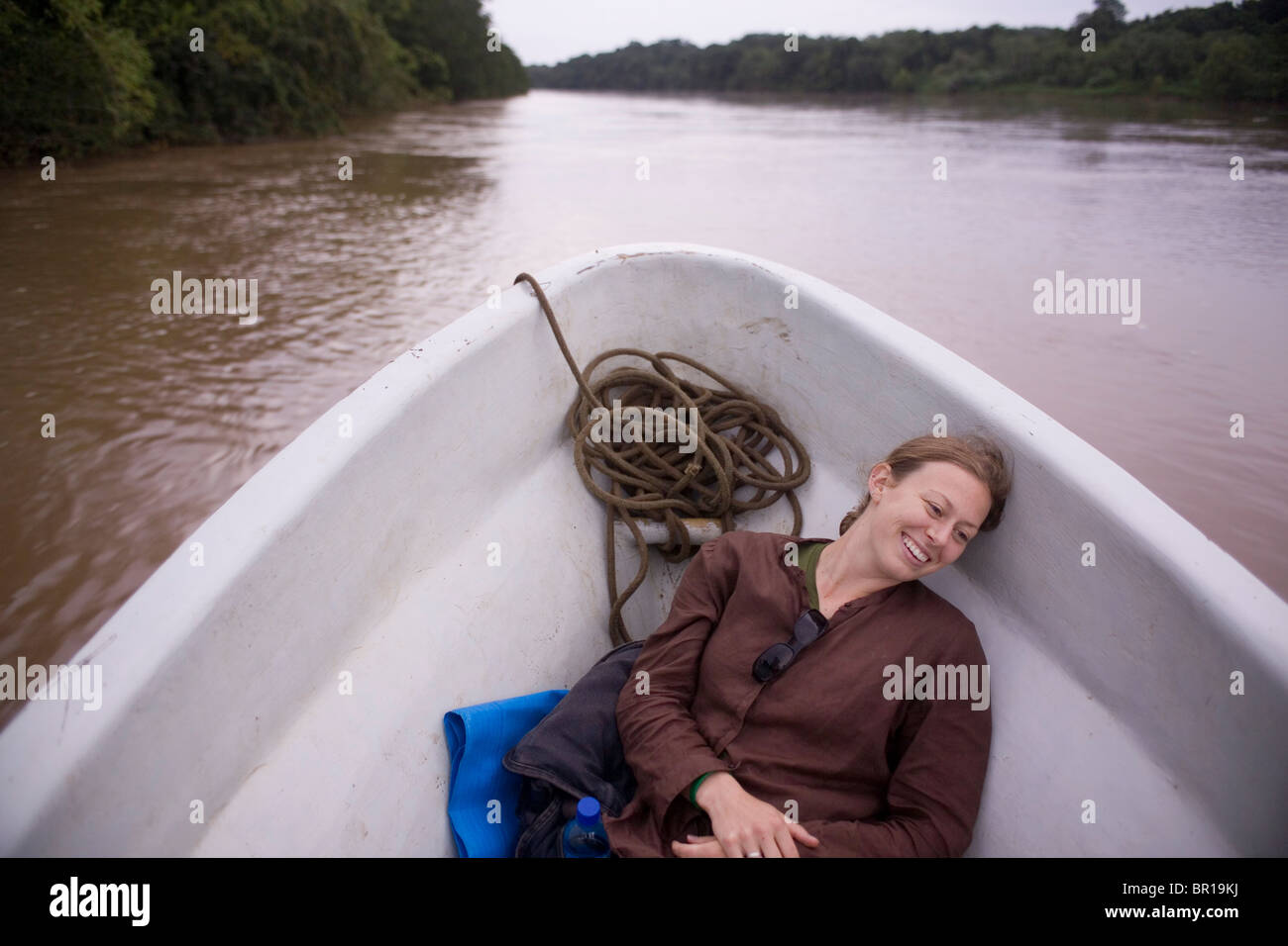 A young woman rests in the bow of the motorboat on her way up the Rio Coco to do relief and aid work in a remote indigenous Misk Stock Photo
