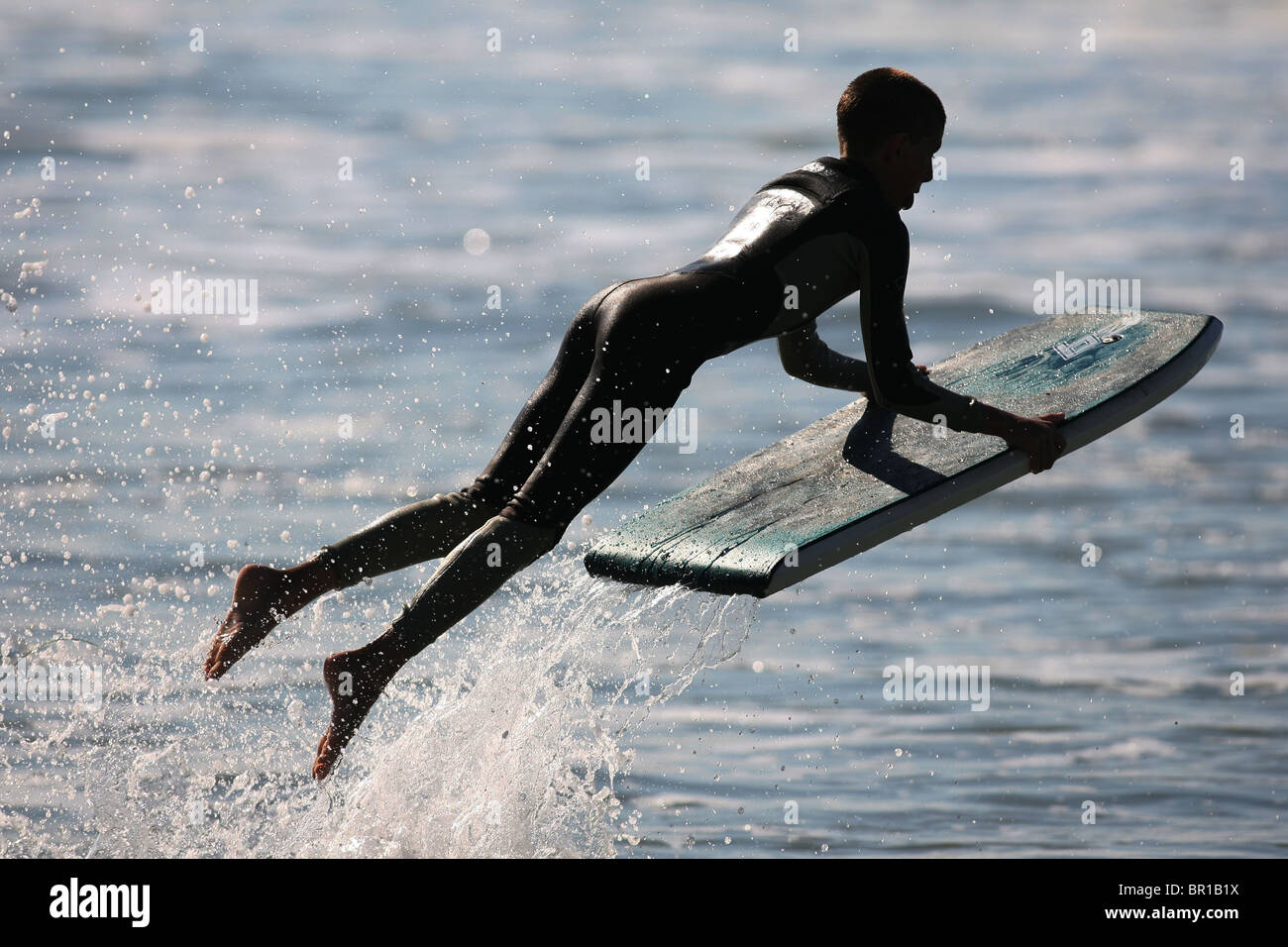 Boy plays in waves on wakeboard Stock Photo