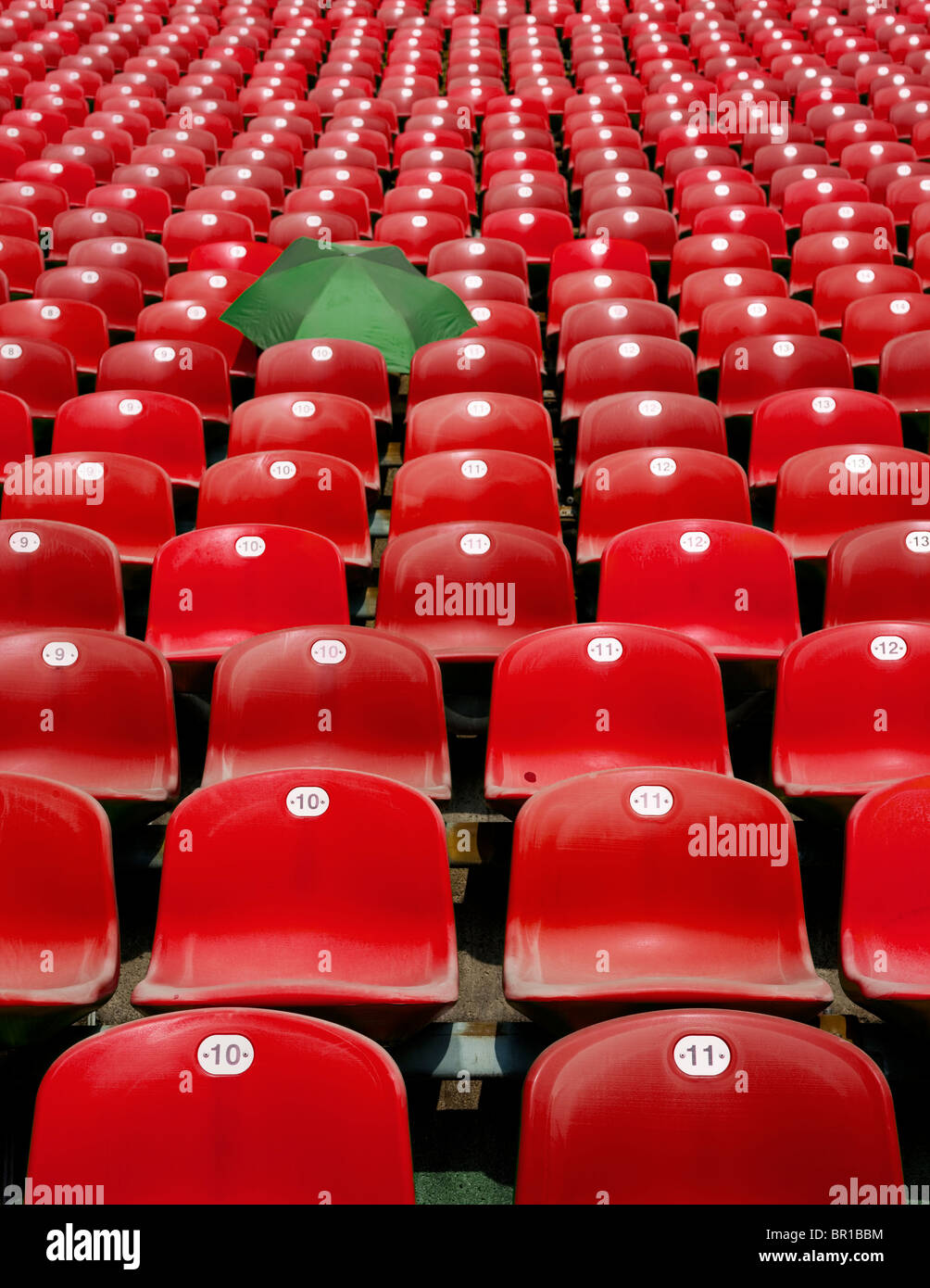 green umbrella left between red seats of bleachers Stock Photo Alamy