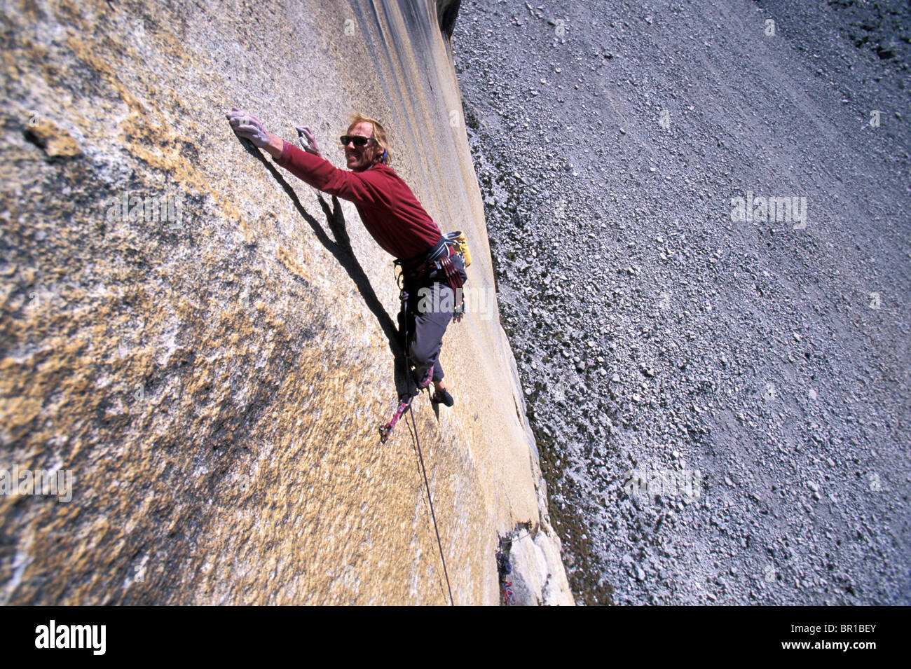 A man reaching for a hold while climbing in Cordillera Blanca, Peru
