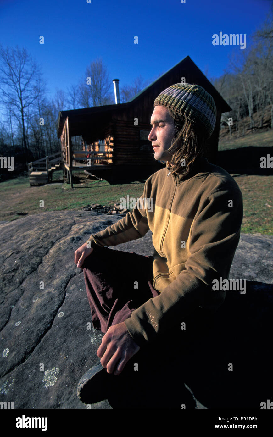 A Male Climber Meditating On A Rock By A Cabin Near Jasper