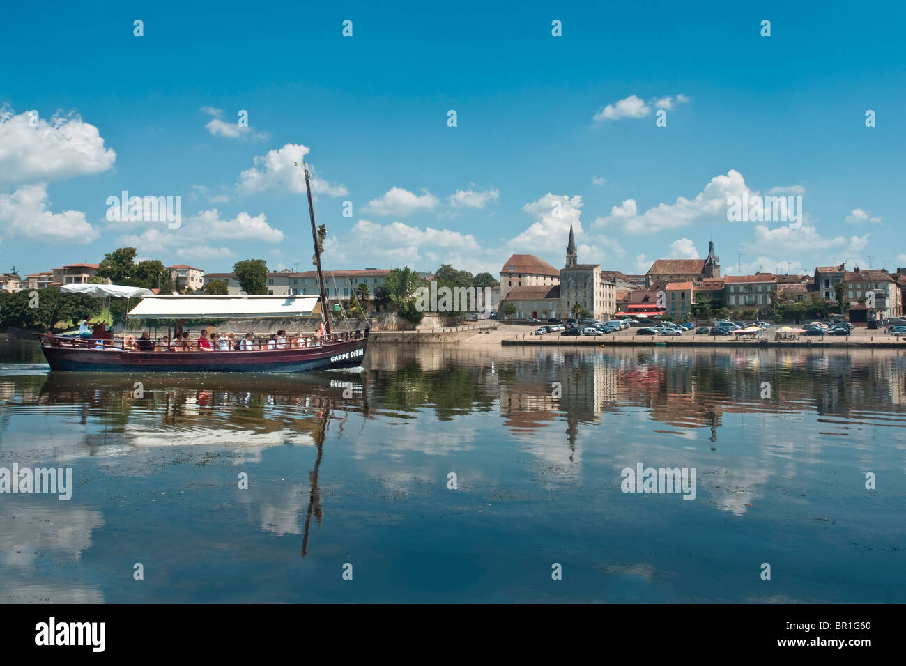 Bergerac, Dordogne, France, seen across the river Dordogne from the south bank, with a river trip boat passing Stock Photo