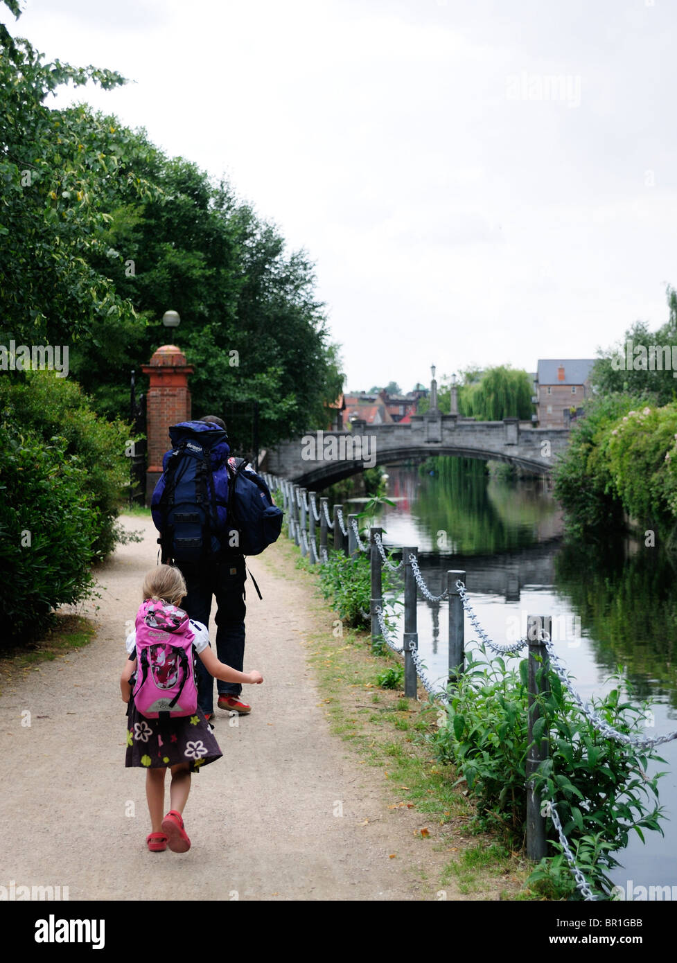 Father and daughter with rucksack on foot by river Stock Photo