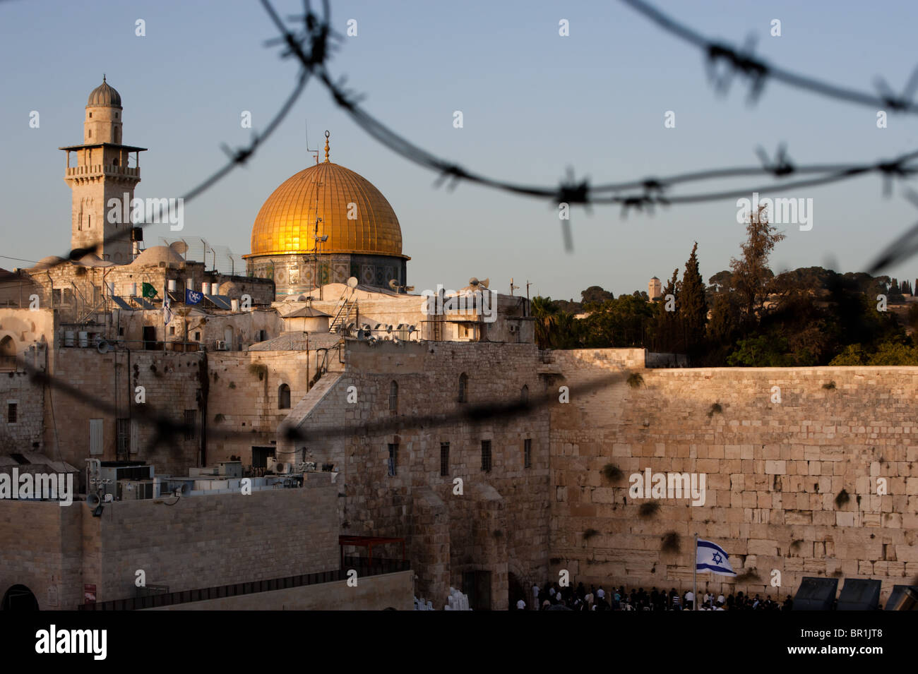 Two of Islam and Judaism's holiest sites, Jerusalem's Dome of the Rock and the Western Wall, seen through barbed wire. Stock Photo