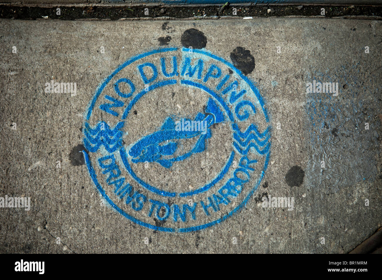 A warning sign, No dumping, drains to New York harbor, seen on sidewalk near storm drain in Chinatown in Manhattan Stock Photo
