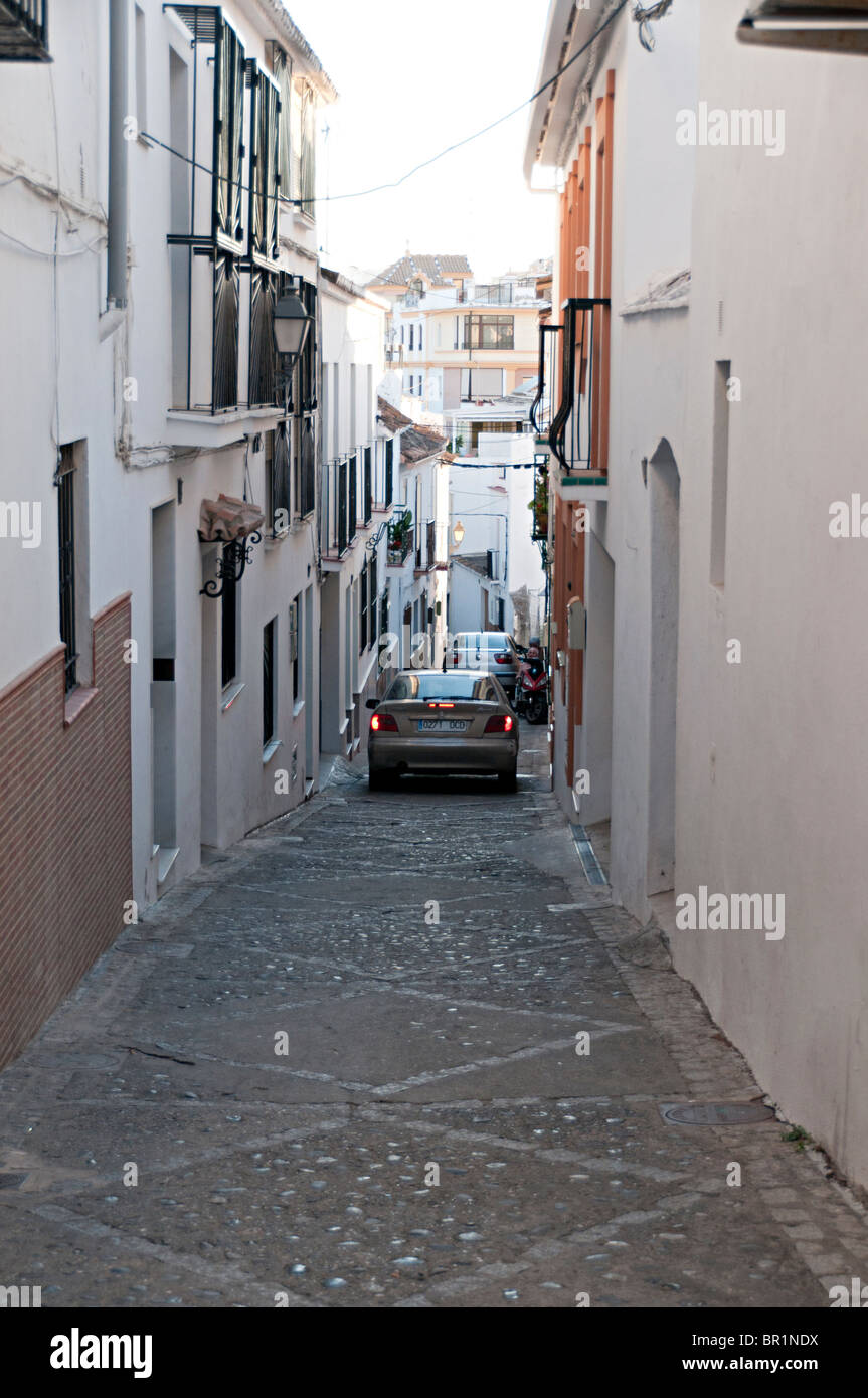 a narrow cobbled street in estepona spain with a car driving down it