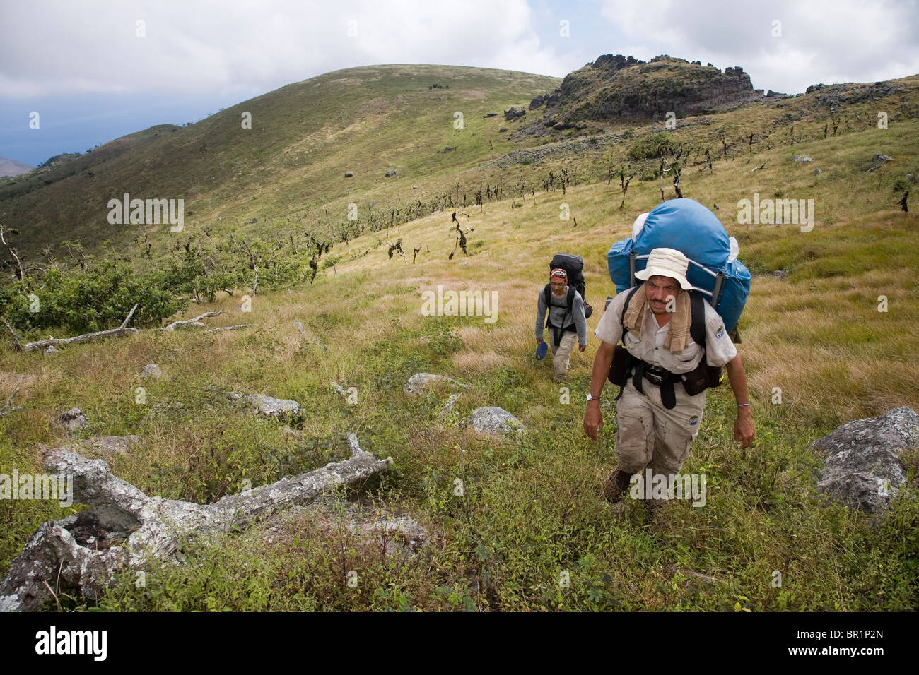 A scientist and his assistant make their way to the summit of Santiago Island in the Galapagos, following in the footsteps of Ch Stock Photo