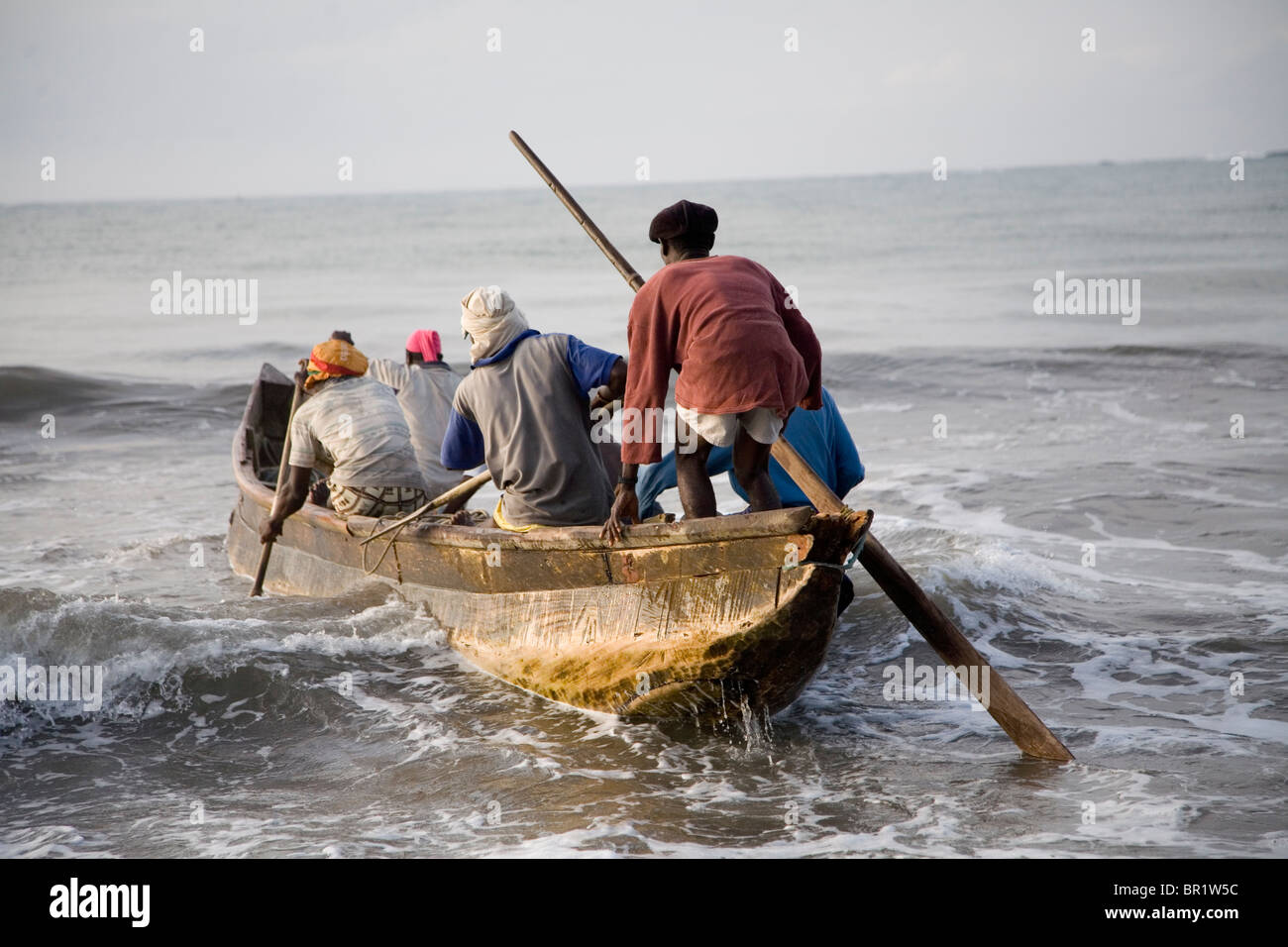 Fishermen in a boat getting into the ocean in Ghana Stock Photo