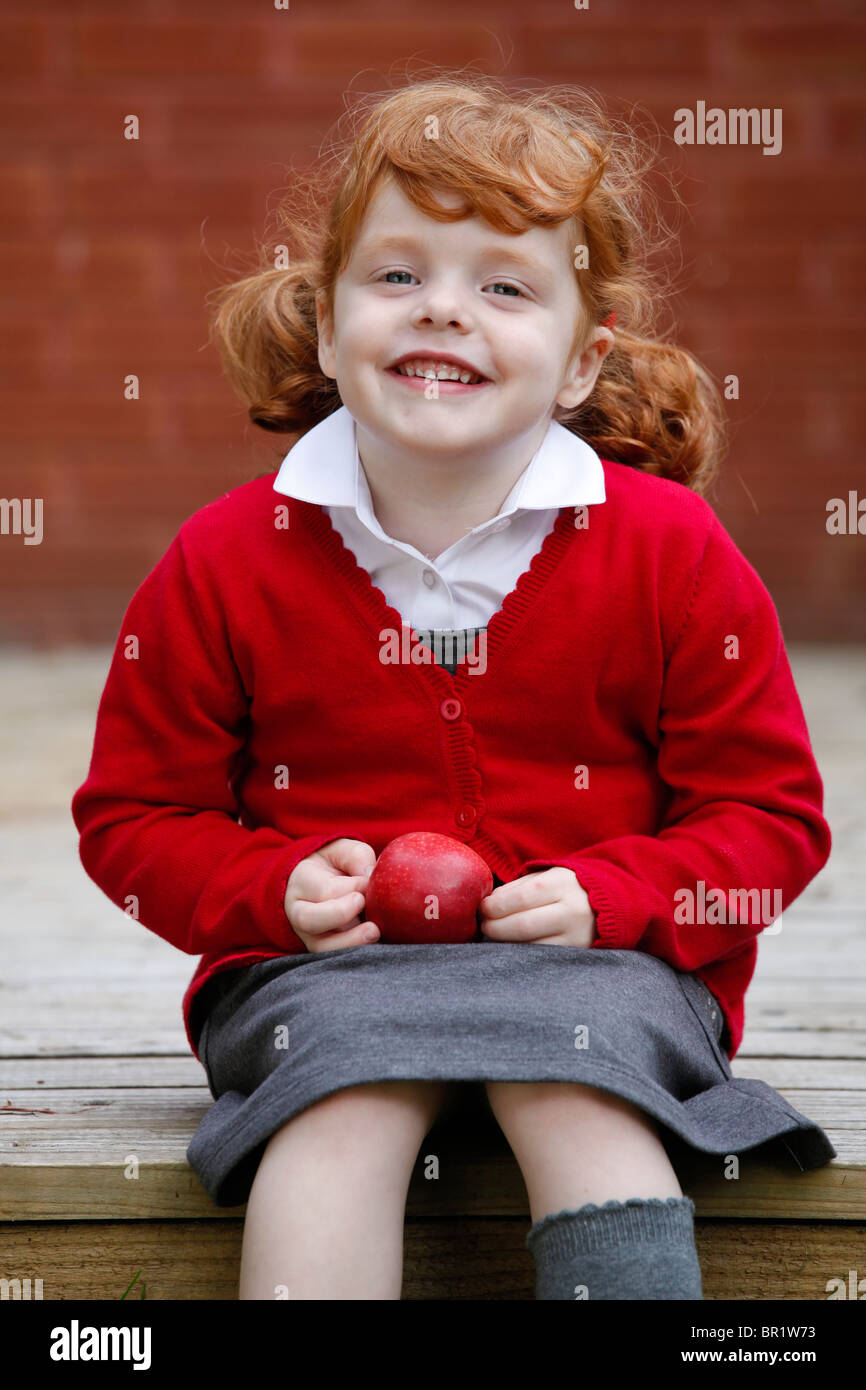 Little girl, age 4, wearing her school uniform in a garden. Stock Photo