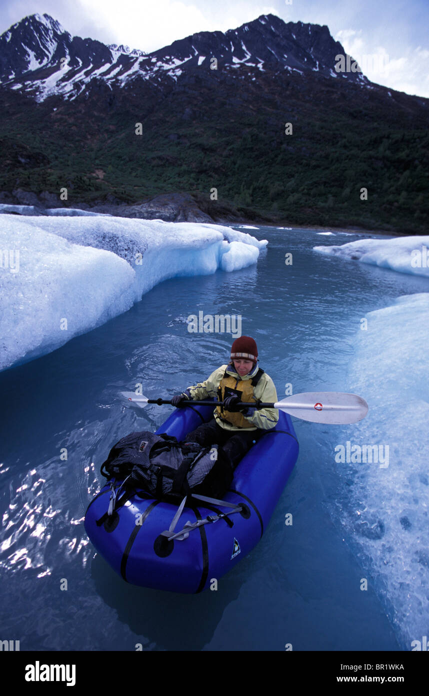 A woman pack rafting between icebergs in Knik River, Alaska. Stock Photo