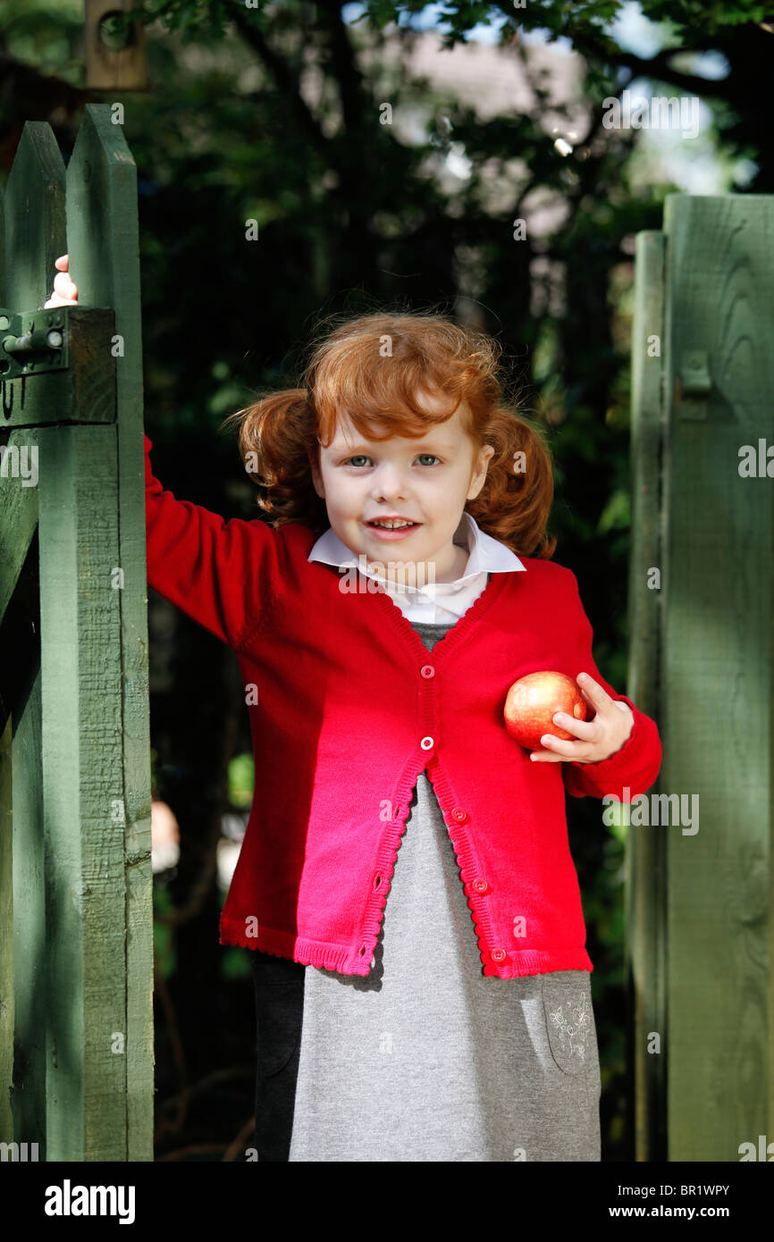 Little girl, age 4, wearing her school uniform in a garden. Stock Photo