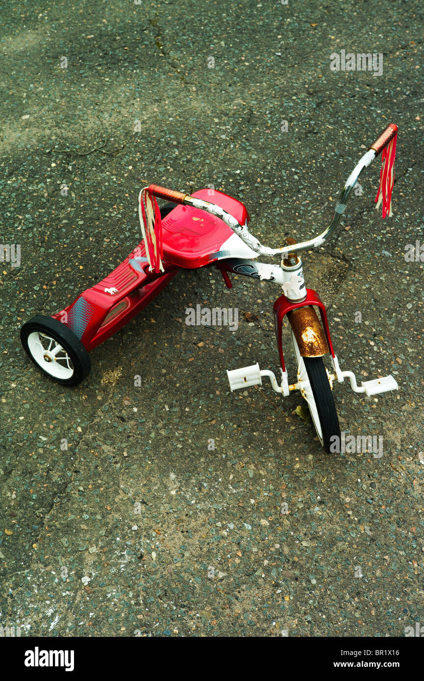 Child's red tricycle with rusting fender. Stock Photo