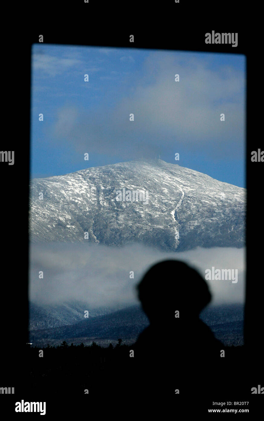 A woman looks at Mount Washington through a window. Stock Photo