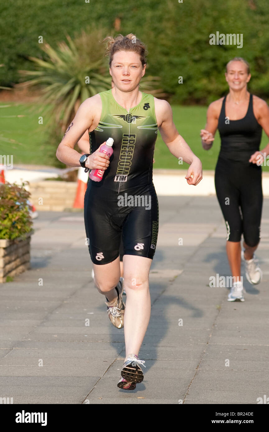 a female triathlete from the Freedom Tri club runs from the transition area after a 400M swim Stock Photo