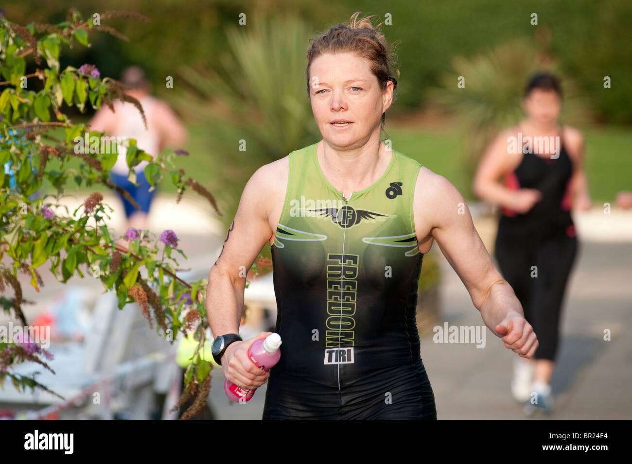 a female triathlete from the Freedom Tri club runs from the transition area after a 400M swim Stock Photo