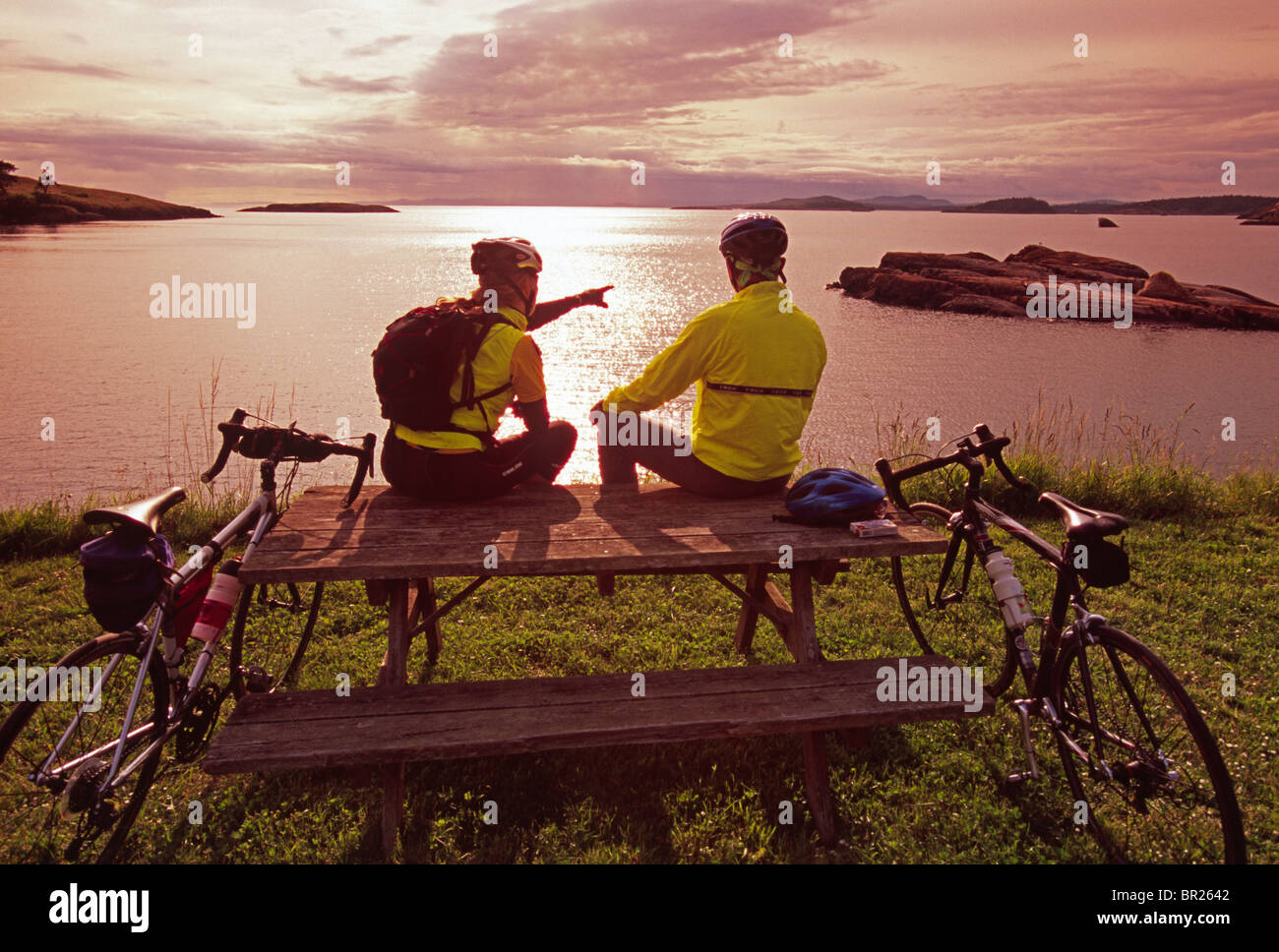 Two bikers, Linda Dugger and Alan Kearney, take a break during a ride on rural Lopez Island. Lopez Island is one of the San Juan Stock Photo