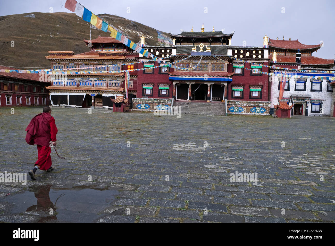 Tagong Monastery Tibetan Buddhist monk rushes across courtyard on way to prayers, Tagong ...