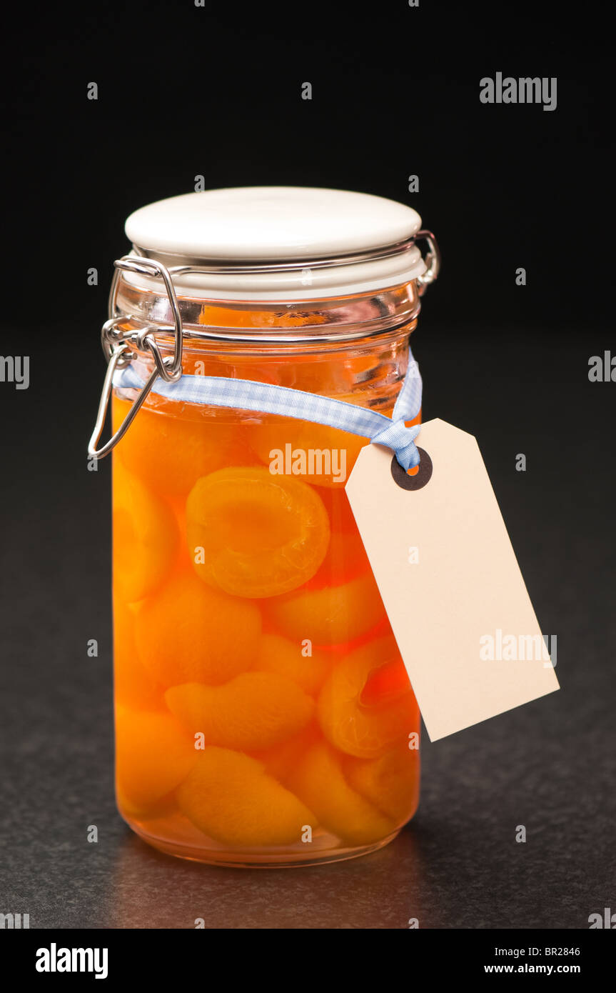 Bottled apricot halves in glass preserve jar with label Stock Photo