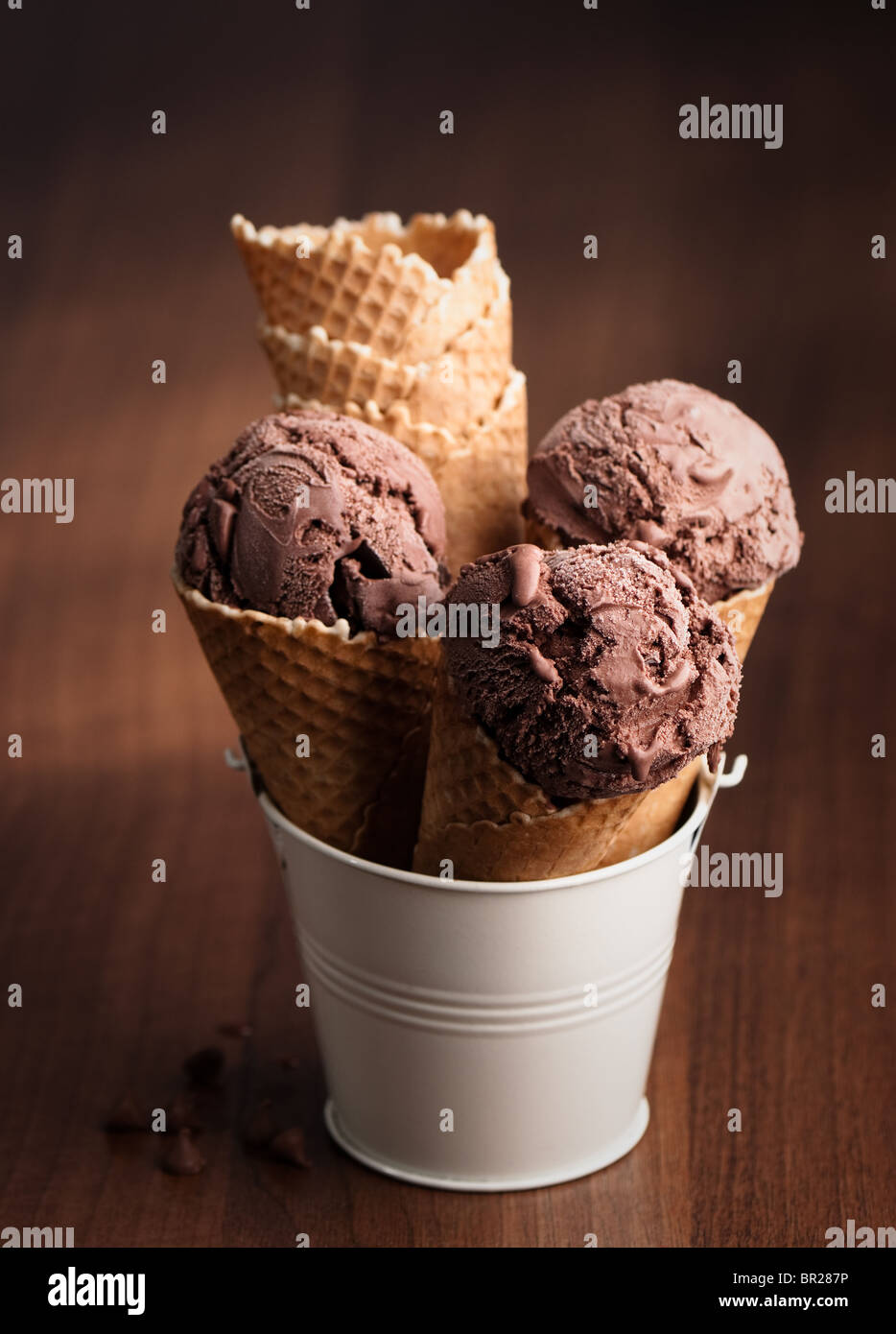 Chocolate ice cream in wafer cones standing in cream coloured metal bucket Stock Photo