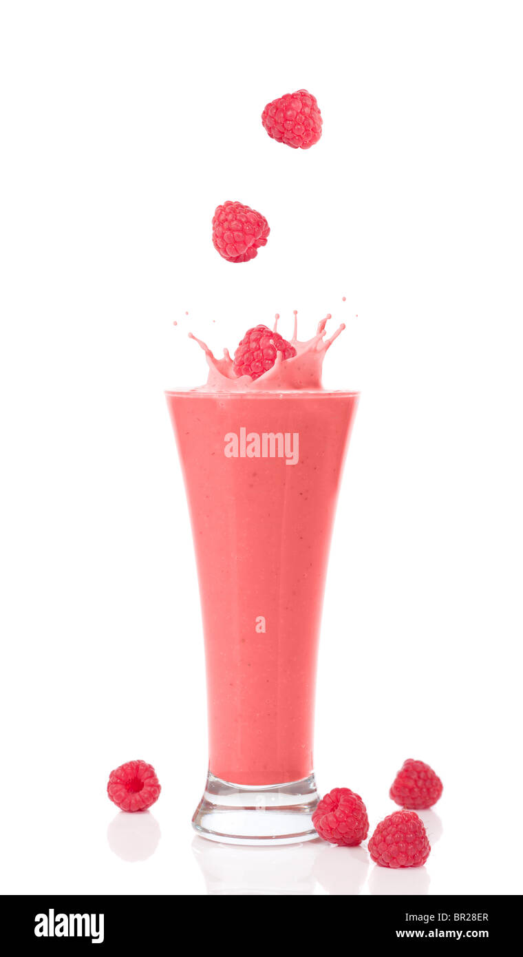 A glass of raspberry and strawberry smoothie with raspberries splashing into the glass Stock Photo