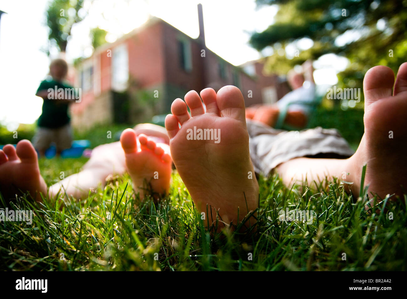 Two small kids laying the grass with toes in the air. Stock Photo