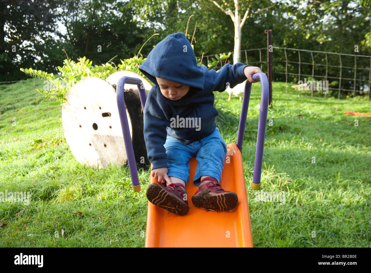 Young boy 18 month old toddler on a slide, Hampshire, England, United