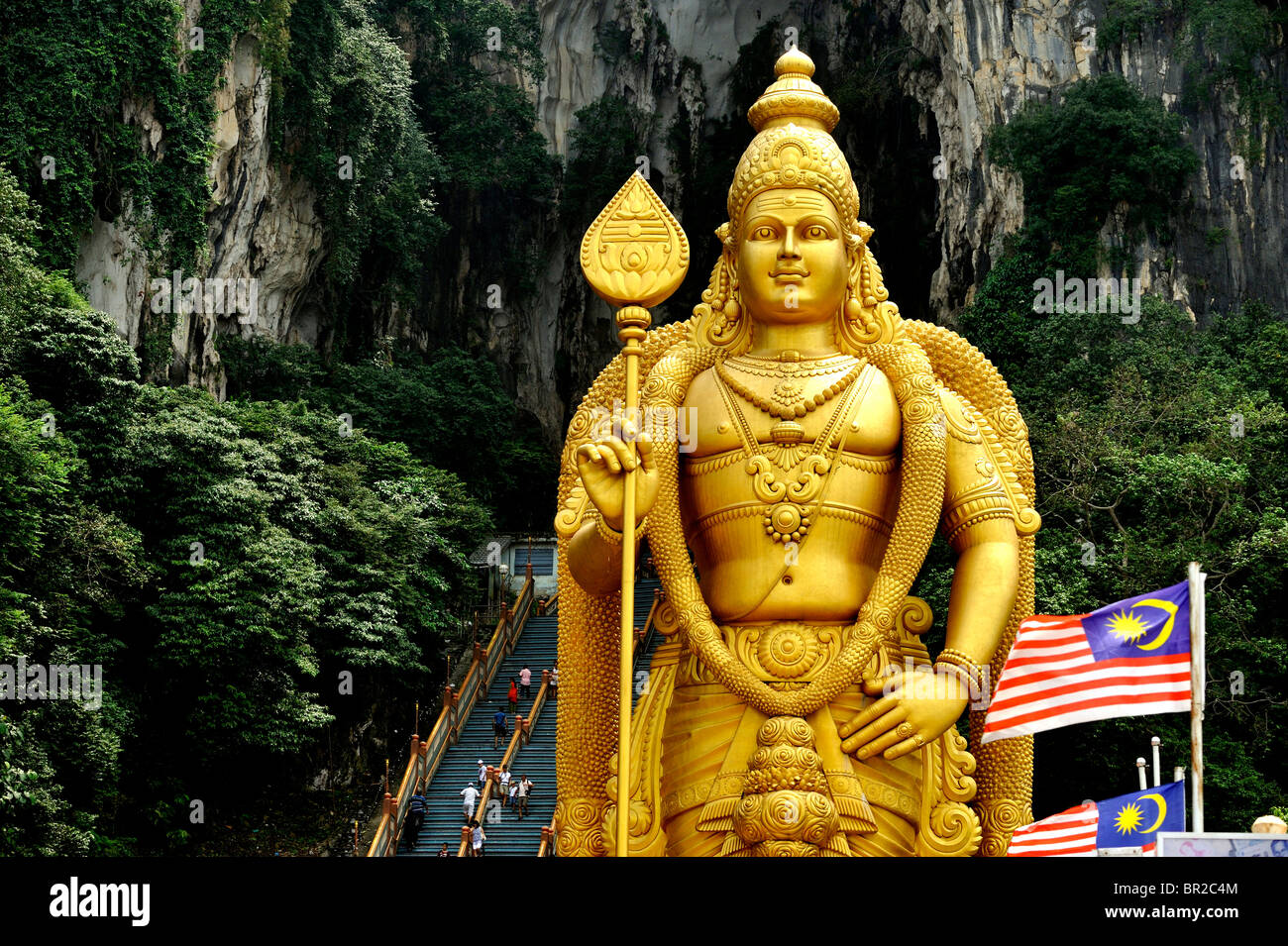 The tall Murugan stands by the stairs climbing the Batu Caves ...