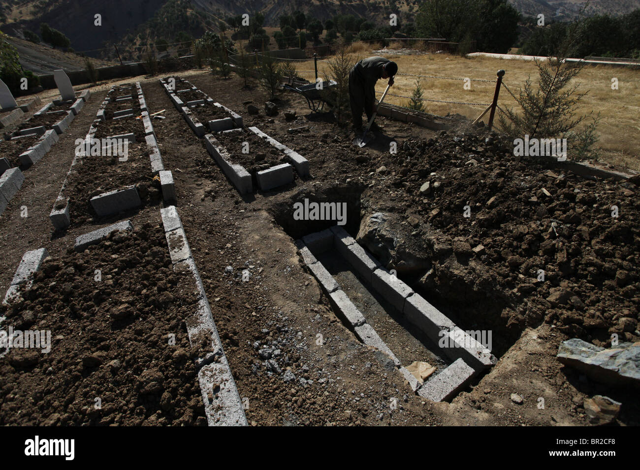 A HPG Kurdish fighter digging up a grave in Mehmet Karasungur Cemetery which is burial site for fallen Kurdish fighters of the People's Defense Forces HPG the military wing of the Kurdistan Workers' Party PKK located in the Qandil Mountains a mountainous area of Iraqi Kurdistan near the Iraq Iran border Stock Photo