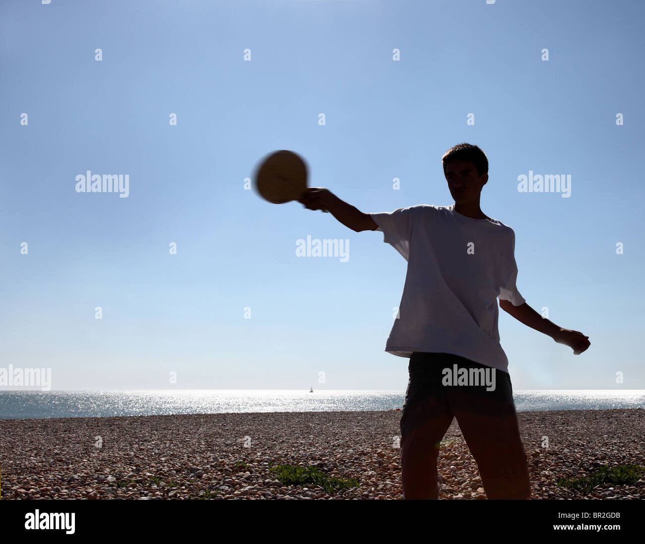 silhouette of a young male with a beach bat Stock Photo