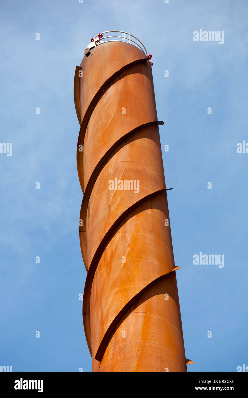 Wind bands ( helical strakes or corkscrew fin )  at the top of a tall steel smokestack used for vibration damping and stops the vortex shedding Stock Photo