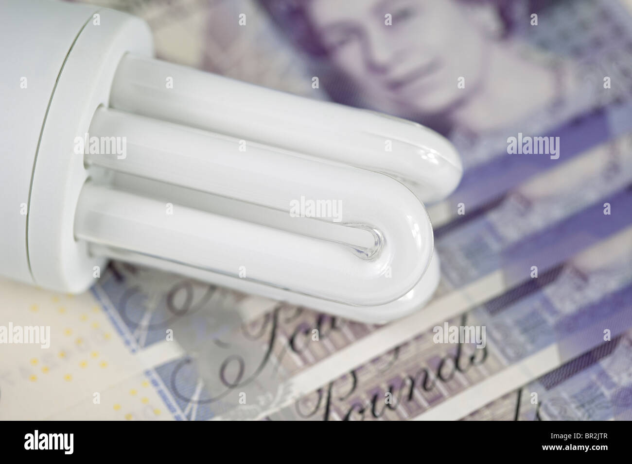 Energy saving lightbulb on a backdrop of UK money. Stock Photo