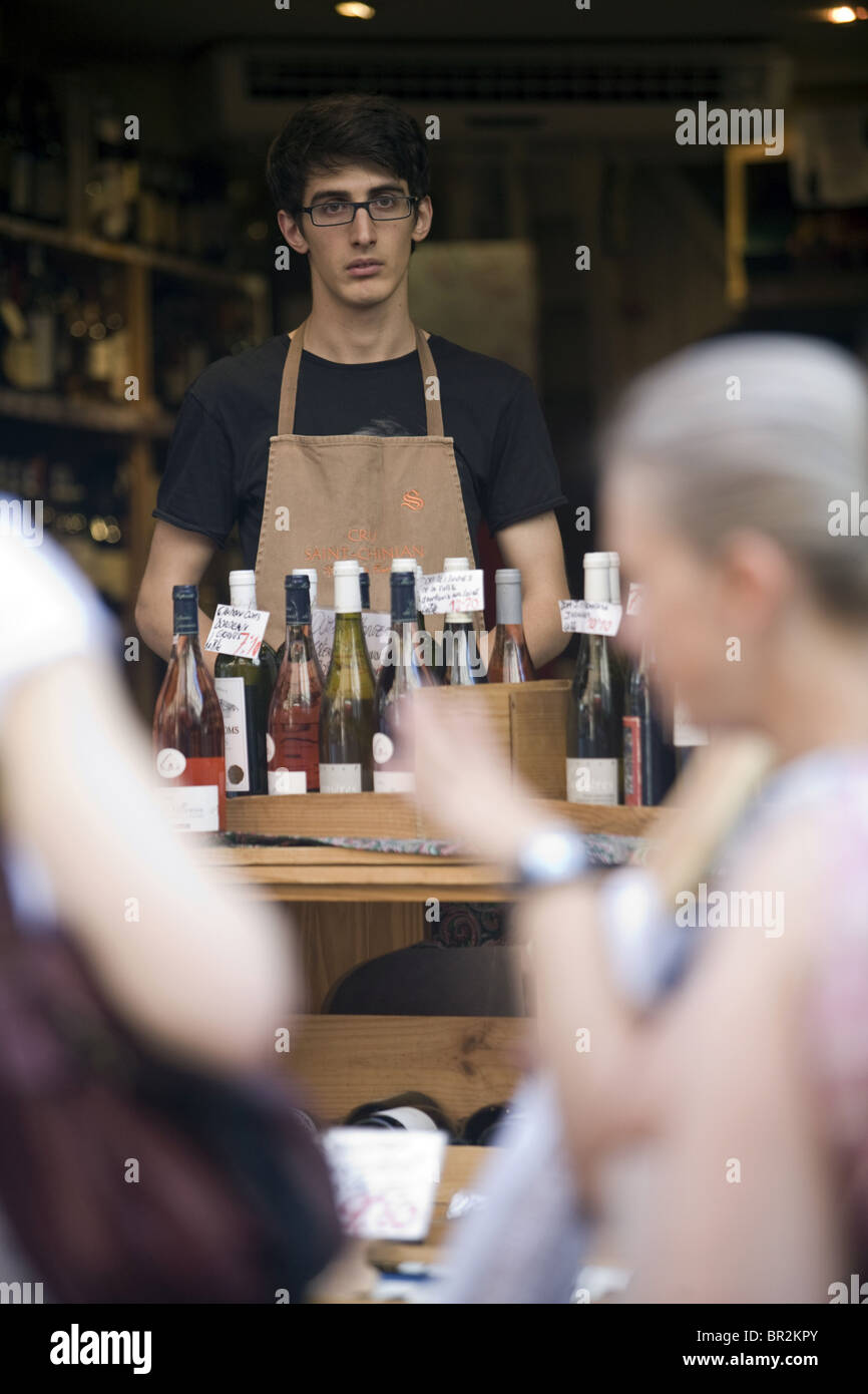 A shop assistant watches potential customers at his wine shop on the Rue Mouffetard, a celebrated food market in Paris Stock Photo