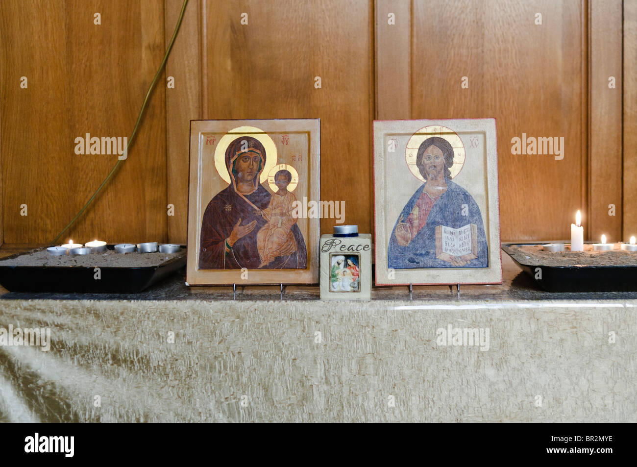 Religious Icons of Madonna and Child and Jesus Christ with candles on a table in a Greek Orthodox church. Stock Photo