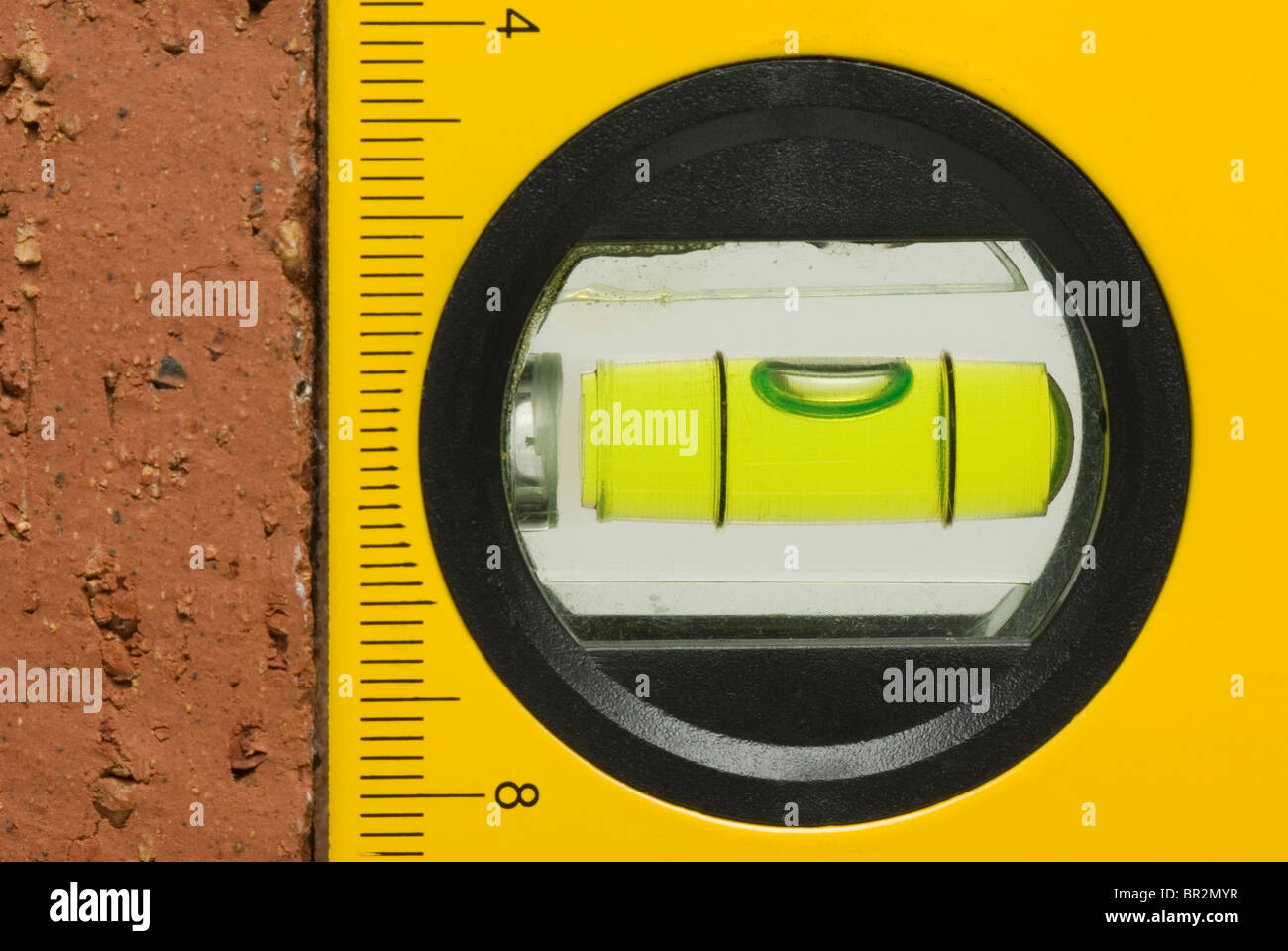 Builder's spirit level against a red house brick Stock Photo